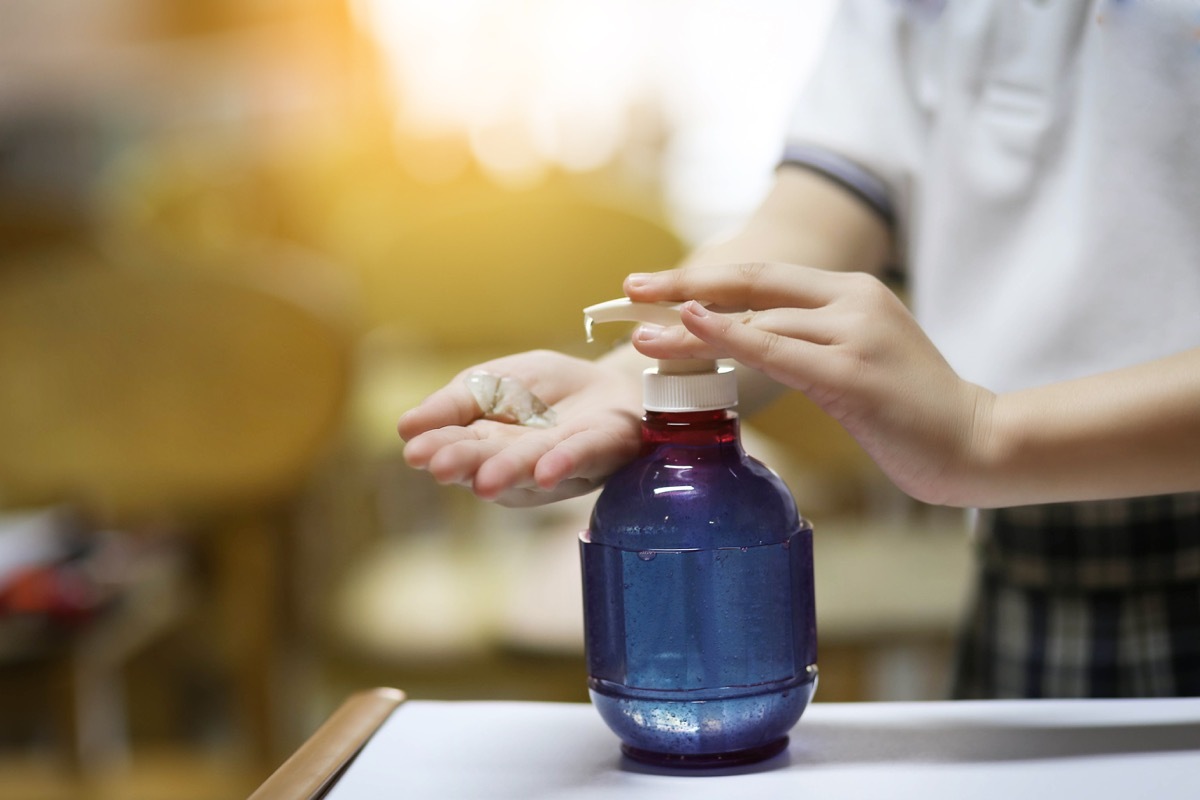 girl applying hand sanitizer in school