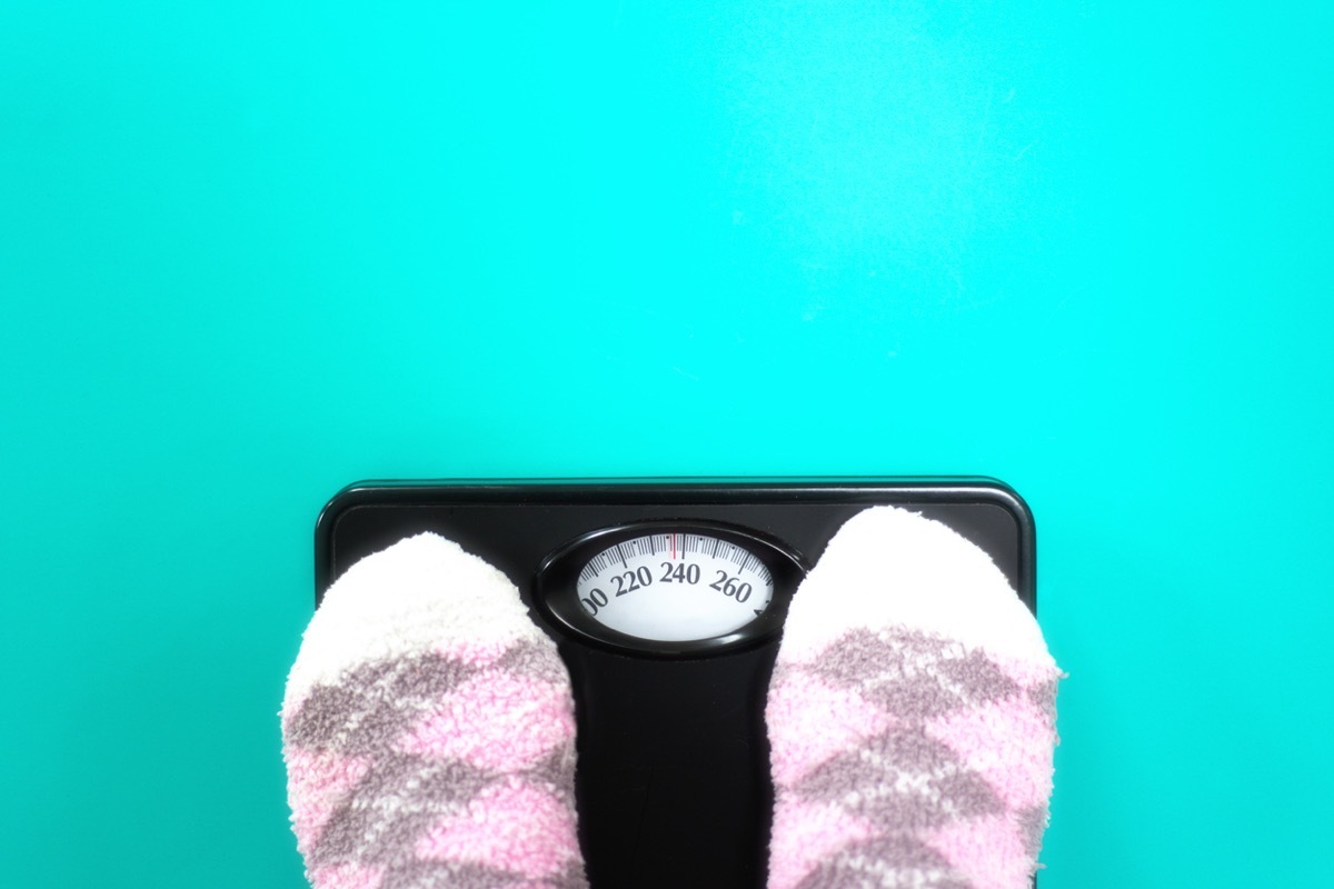 Feet in fuzzy pink socks standing on scale reading (almost) 240 pounds.