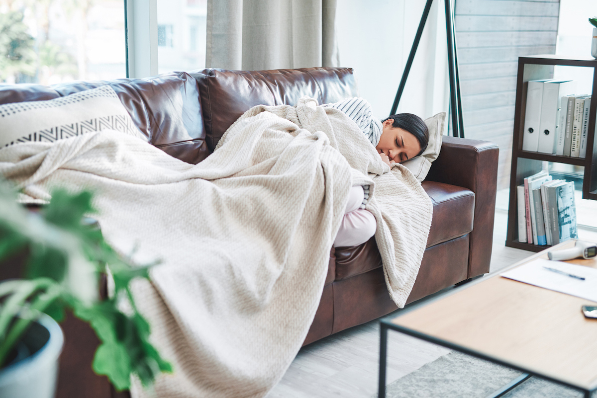 Shot of a young woman feeling sick on the sofa at home