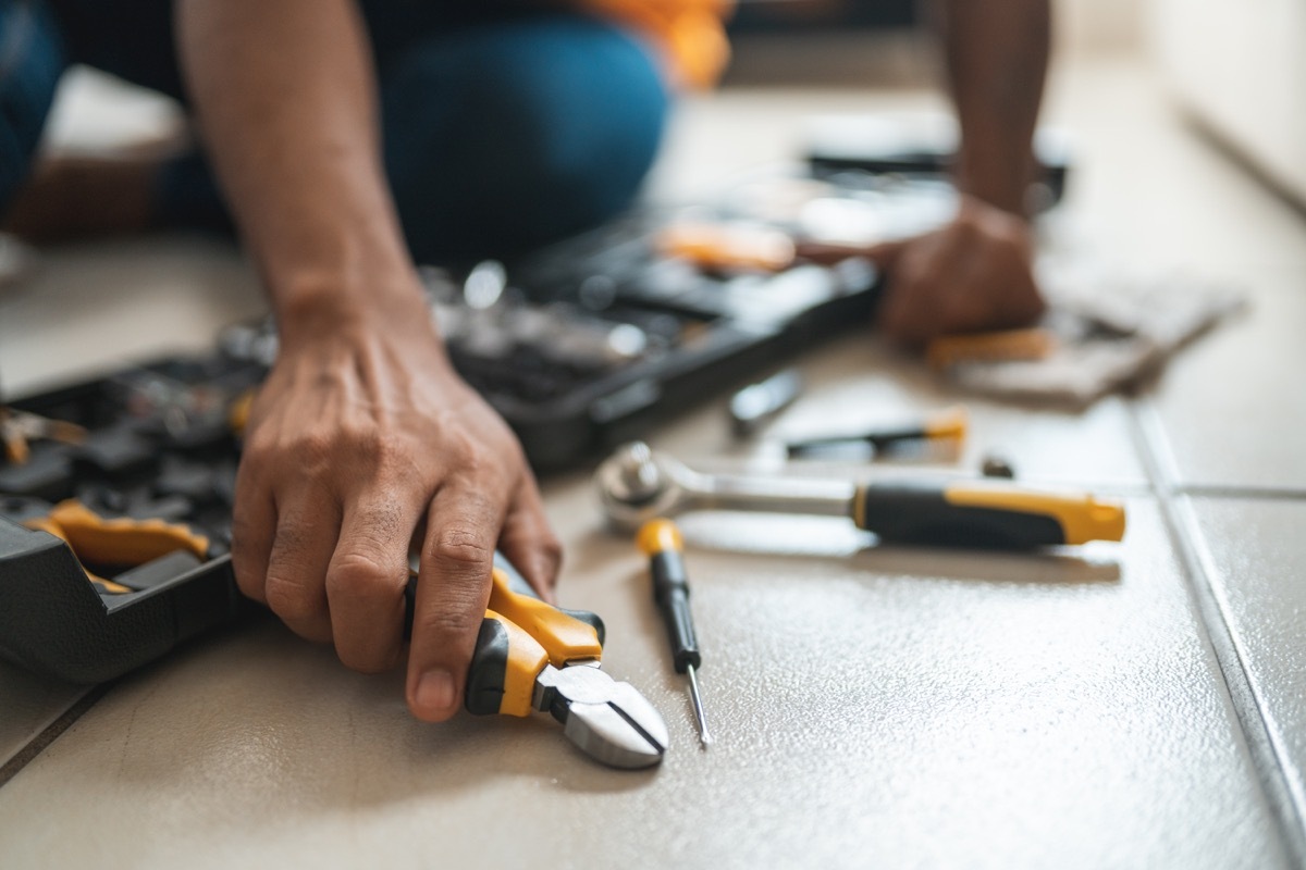 Close up of a man's hand reaching for a wrench among a tool box