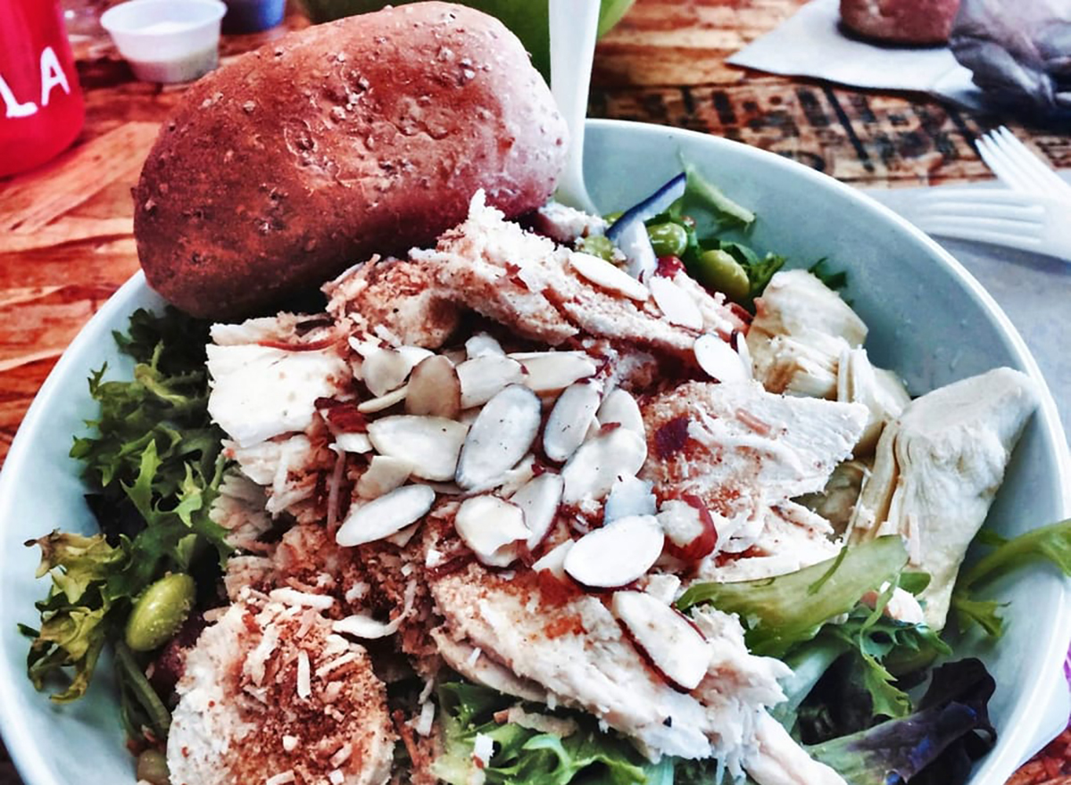 salad topped with coconut chicken and almond slivers