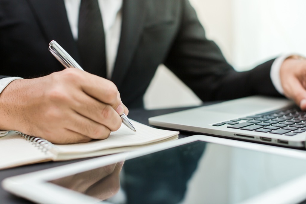 man writing and using laptop