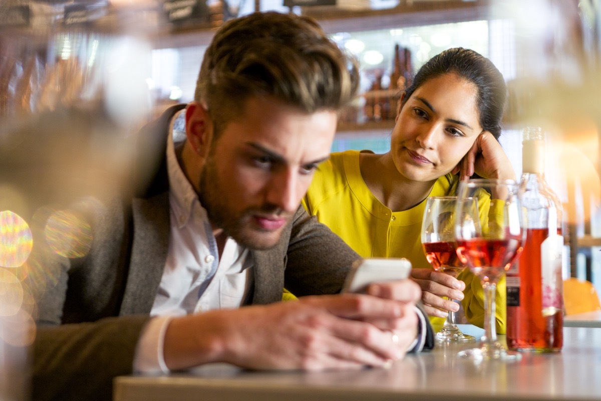 young couple on a date with the man on his phone ignoring the annoyed woman