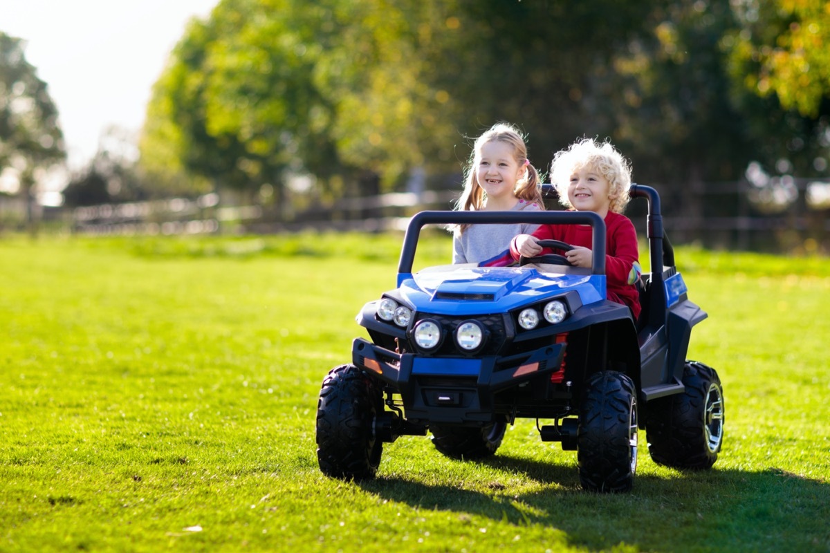 two little kids riding in ride on toy or utv