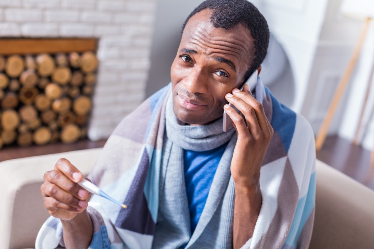 man holding a thermometer and looking at you while talking on the phone