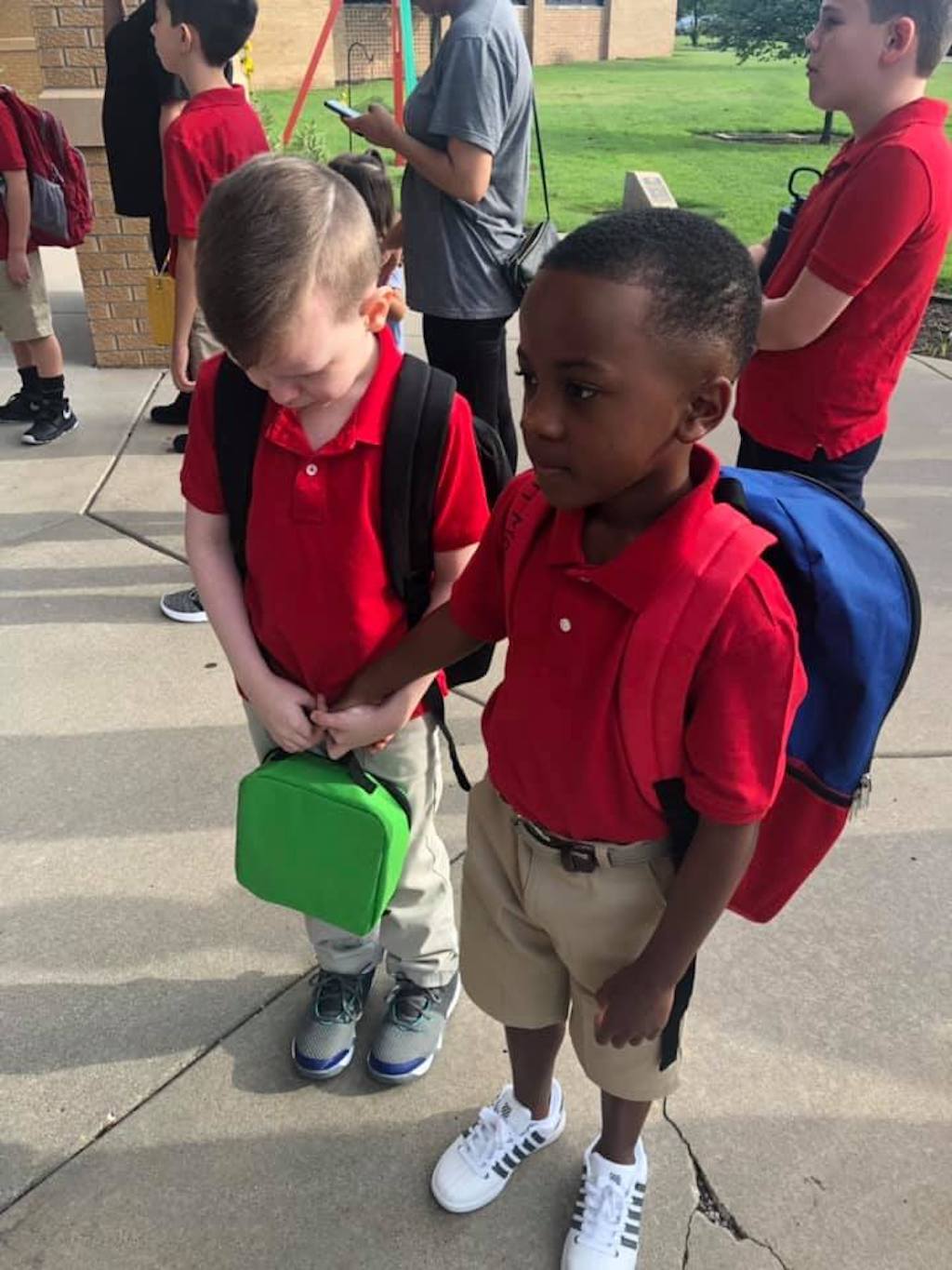 Christian holds hand of autistic boy Connor on the first day of school