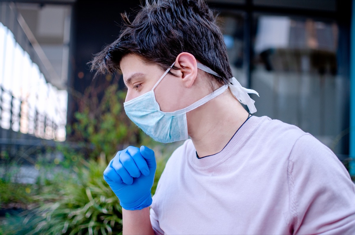 white man coughing into gloved hand