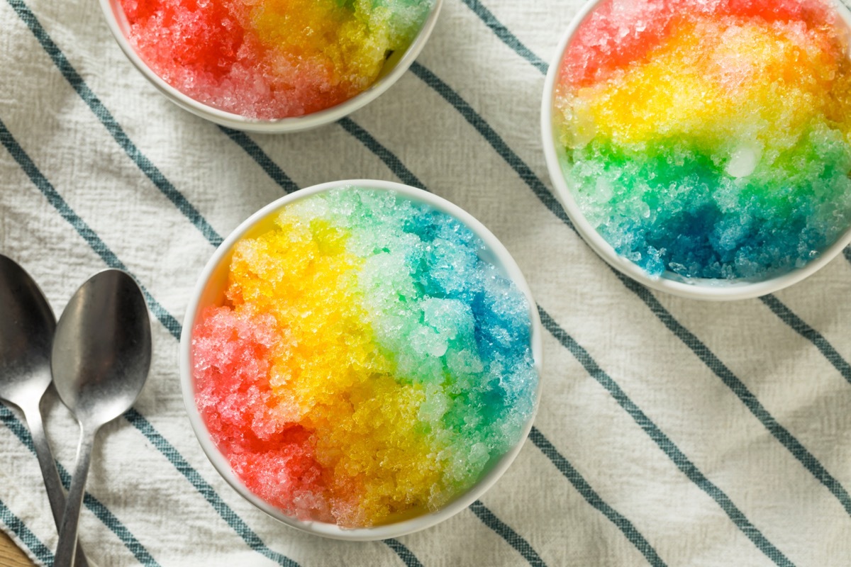 bowls of rainbow snow cones or shaved ice on striped tablecloth