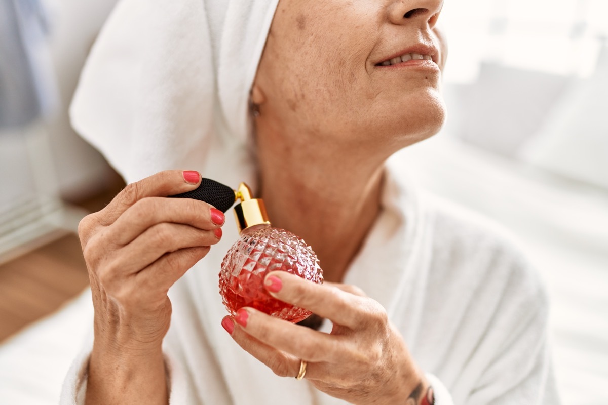 older woman spraying perfume