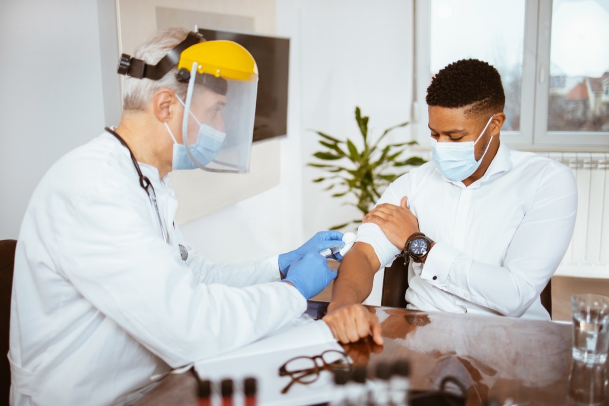 Senior male doctor vaccinates a young man in a doctor's office