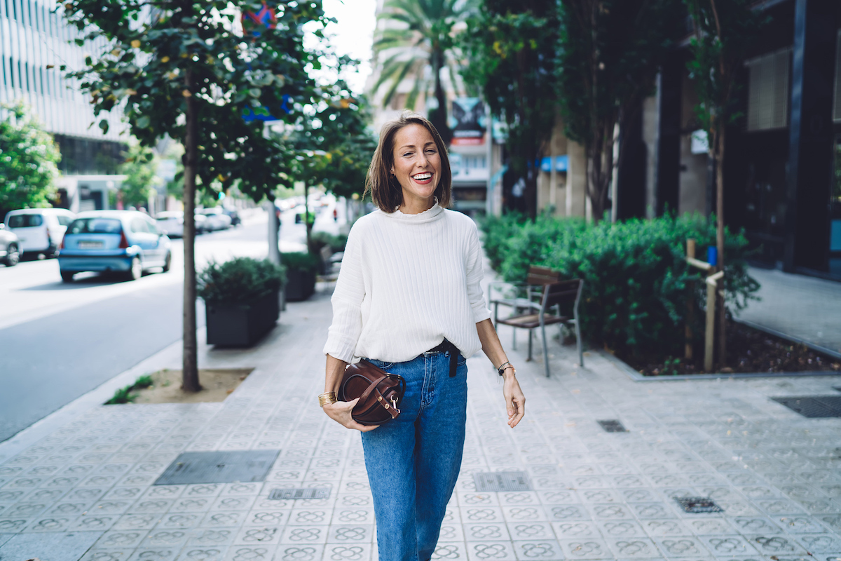 woman walking through street with bag