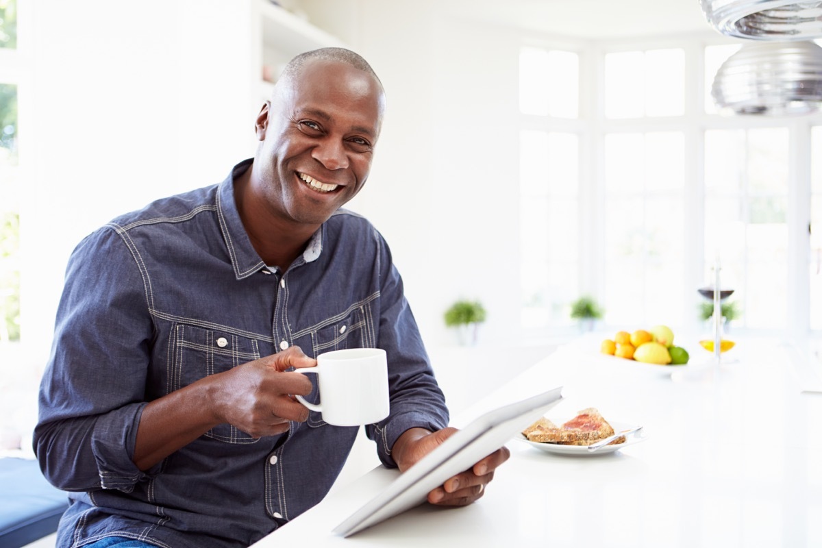 man holding coffee smiling with breakfast