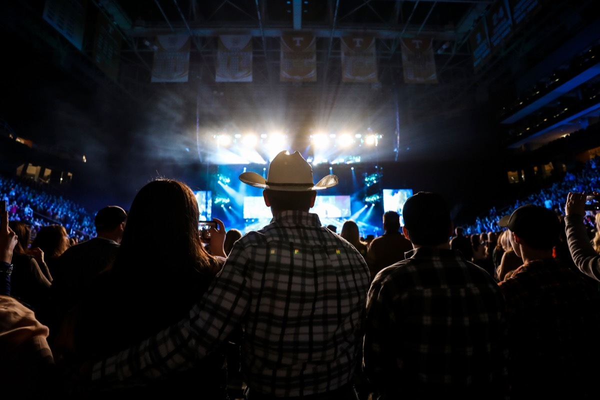 A country music fan watches a live concert wearing a cowboy hat.