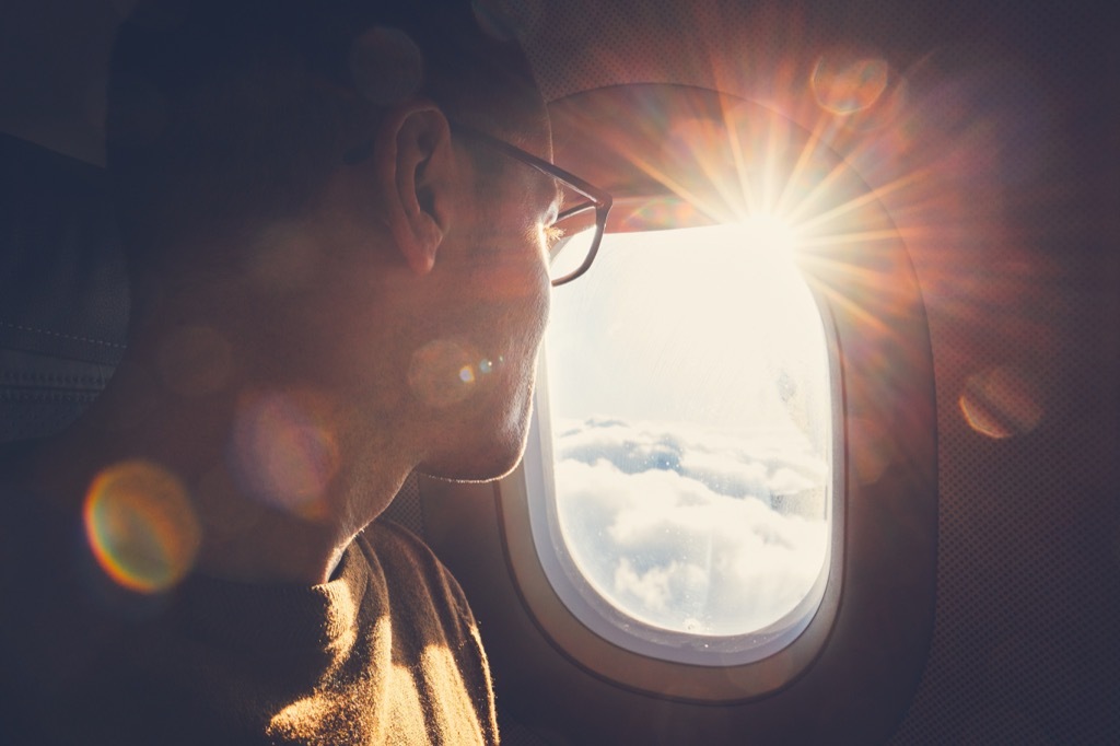 man wearing glasses looking out airplane window