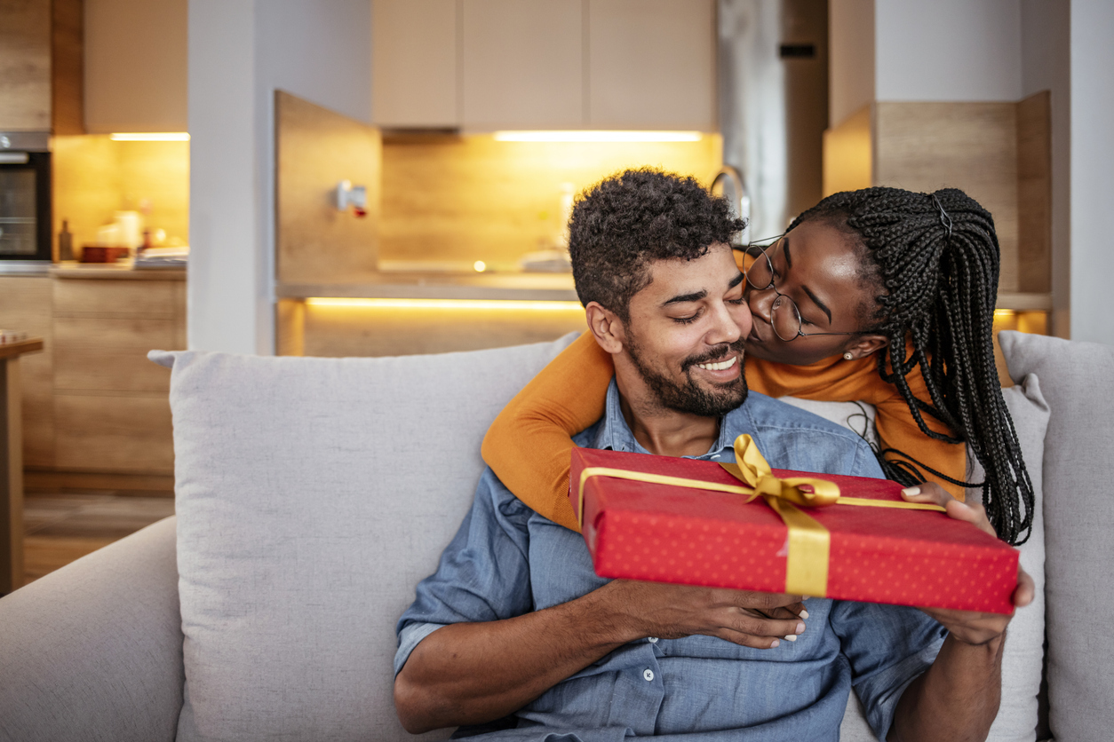 Romantic Couple Exchanging Christmas Gifts At Home. Husband And Wife Affectionately Exchanging Christmas Gifts