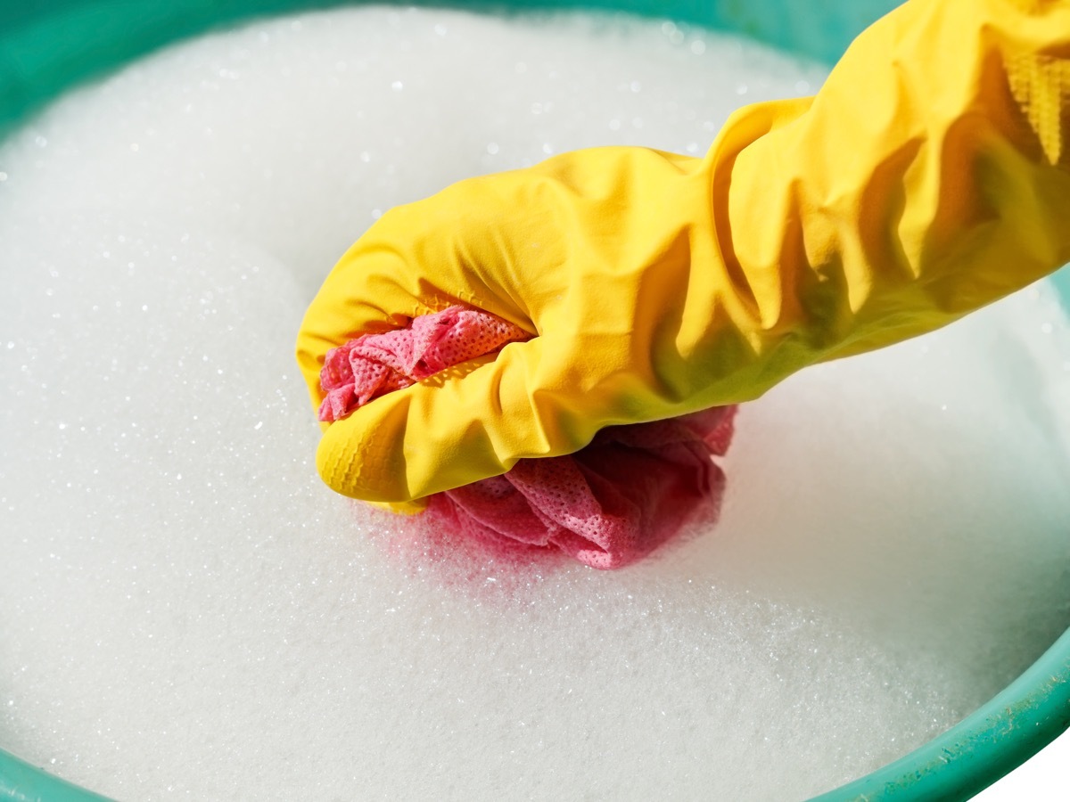 hand in yellow glove in bucket of soapy water