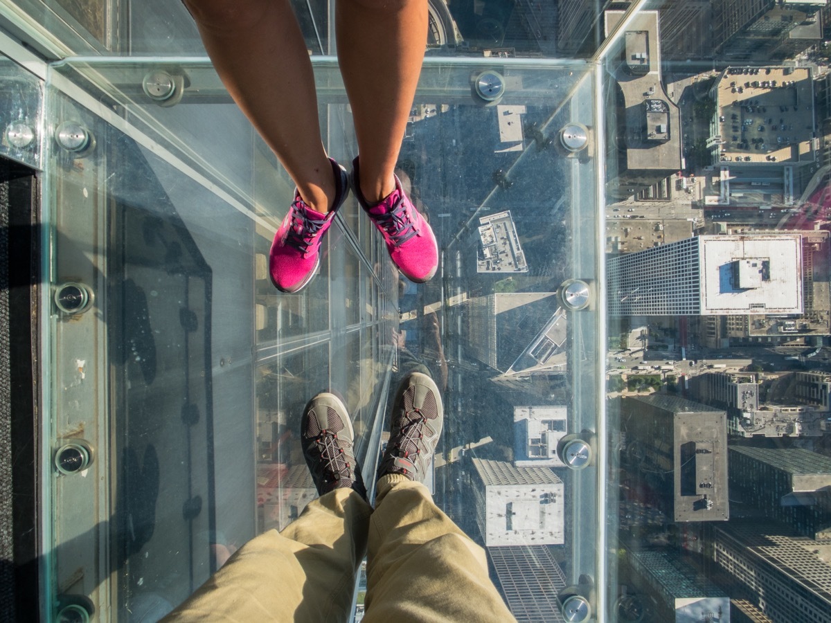 Tourists posing on a glass floor in a skyscraper