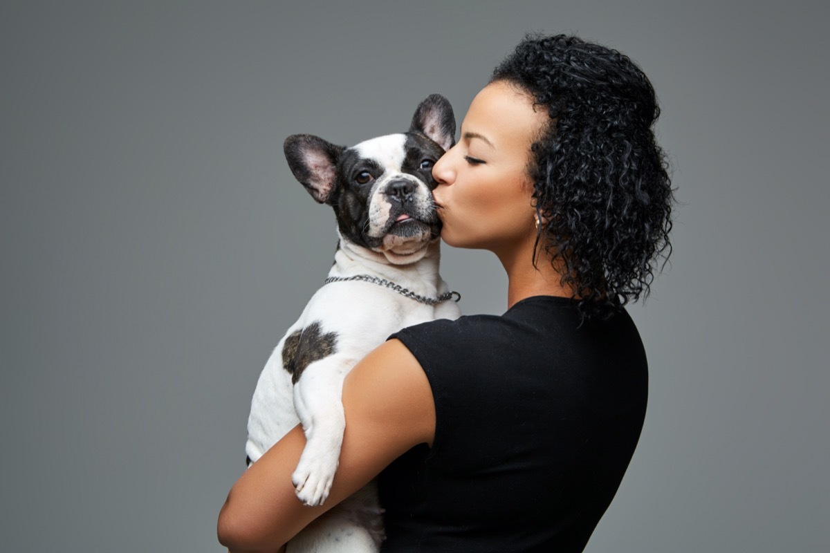 Young woman kissing French bulldog