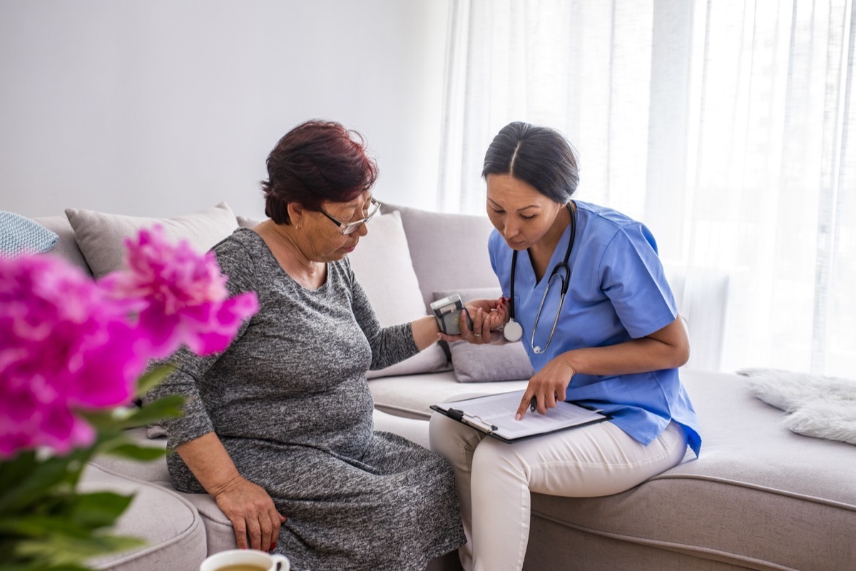 nurse doing blood pressure monitoring for senior woman at home