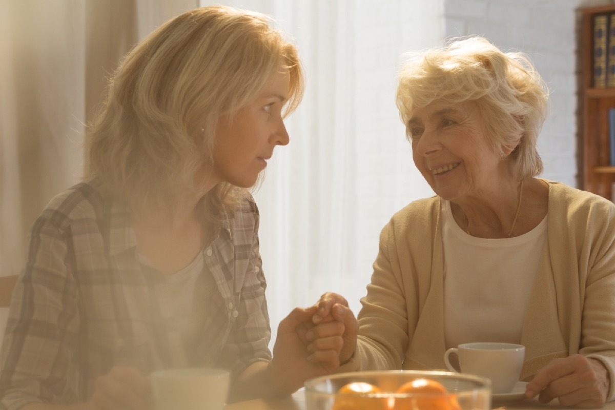 Senior woman smiling at daughter who looks concerned