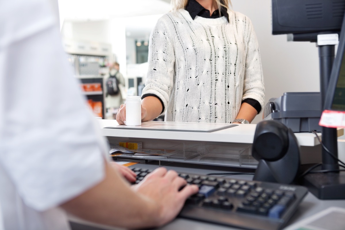 Mid-section of customer standing at checkout counter in drugstore