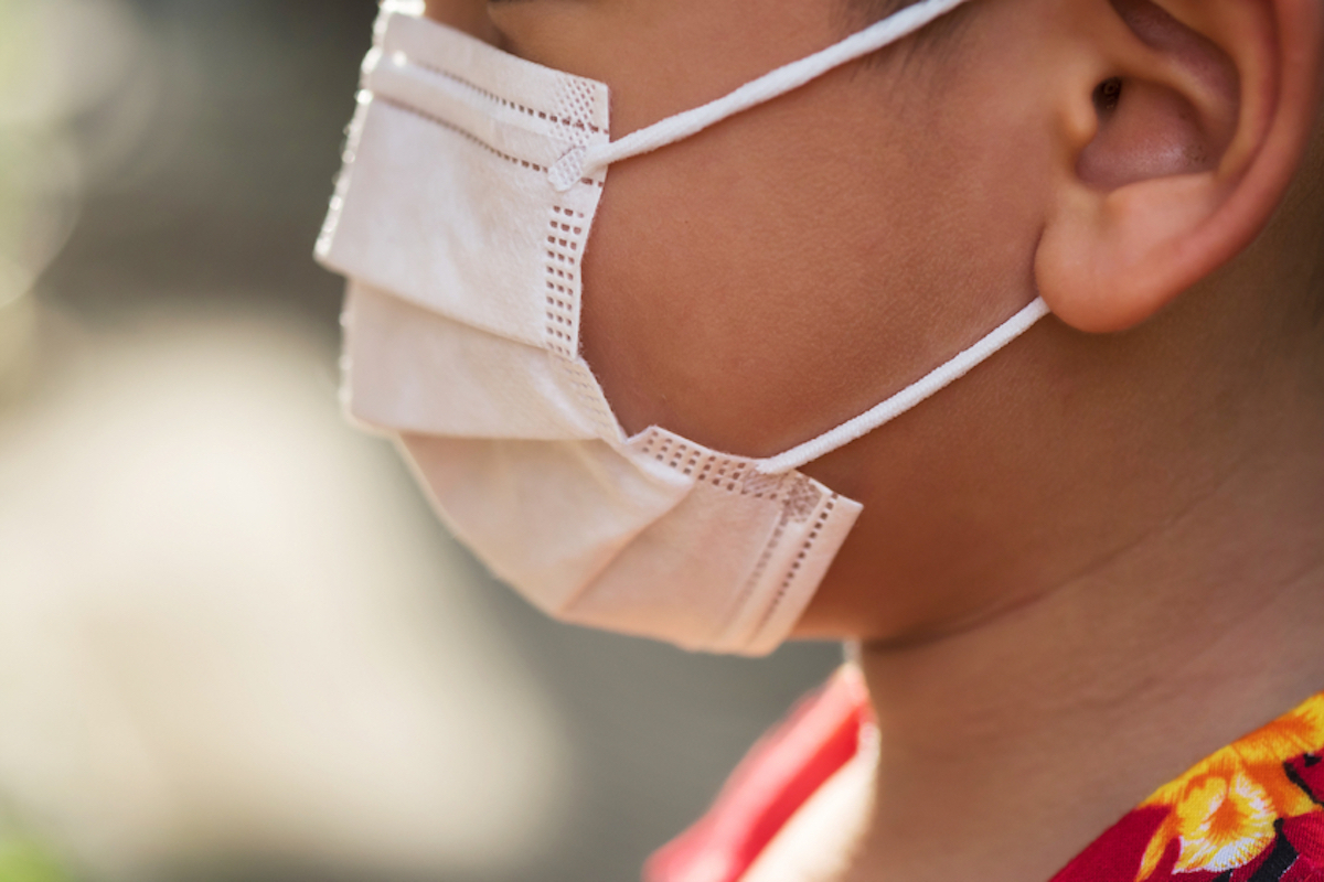 closeup of boy with hawaiian shirt on wearing a mask, profile shot