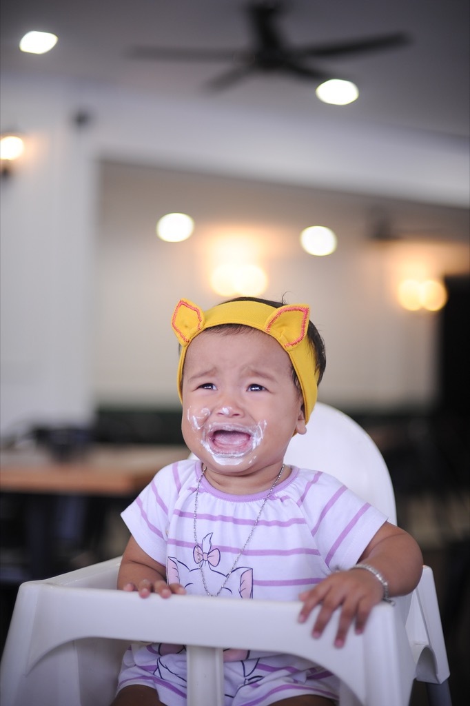 messy, crying baby in high chair