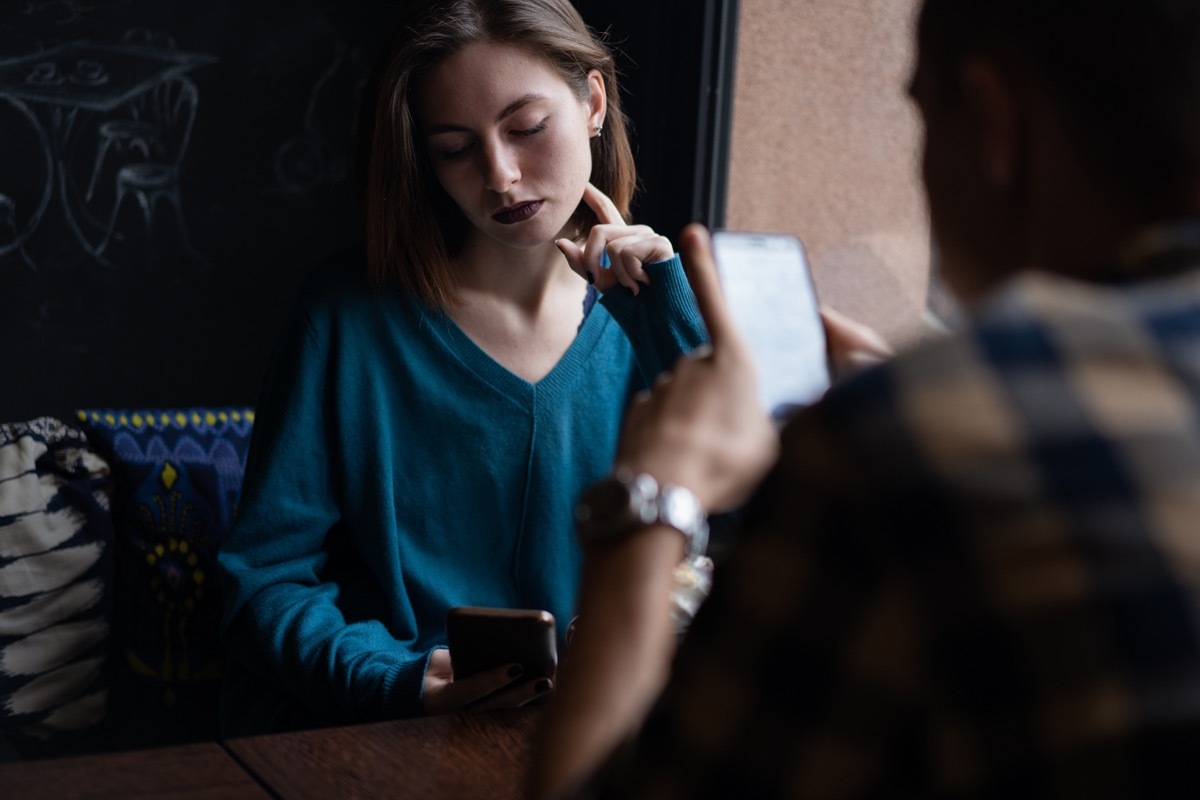 Young couple obsessed with social media ignoring each other in a cafe.