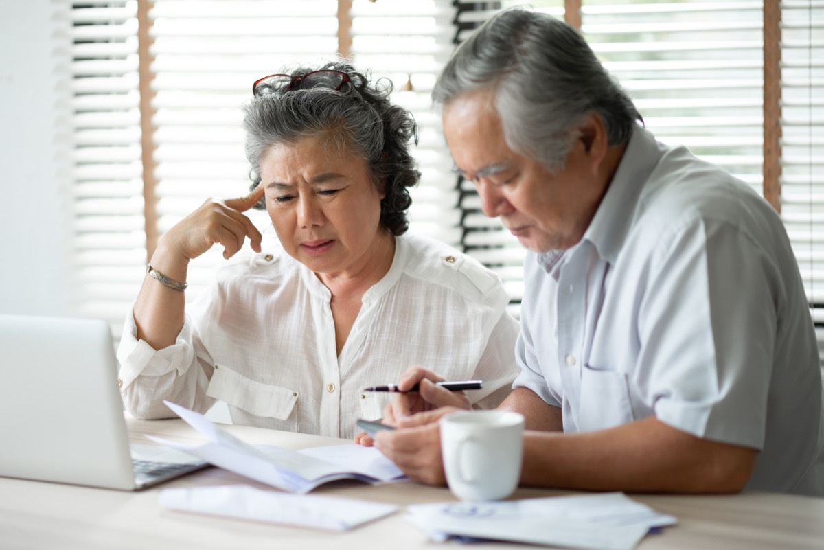 serious asian couple looking stressed and annoyed overpaper work