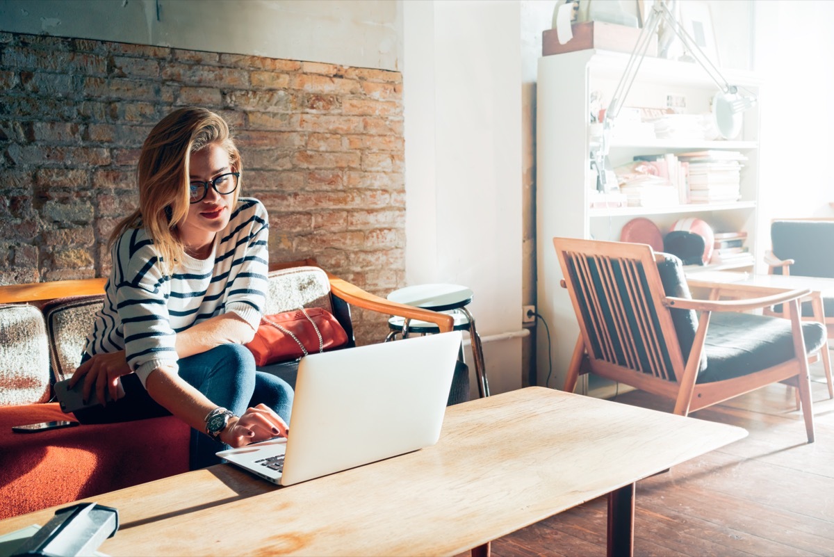 Woman in a cafe looking at her computer wearing a striped sweater.