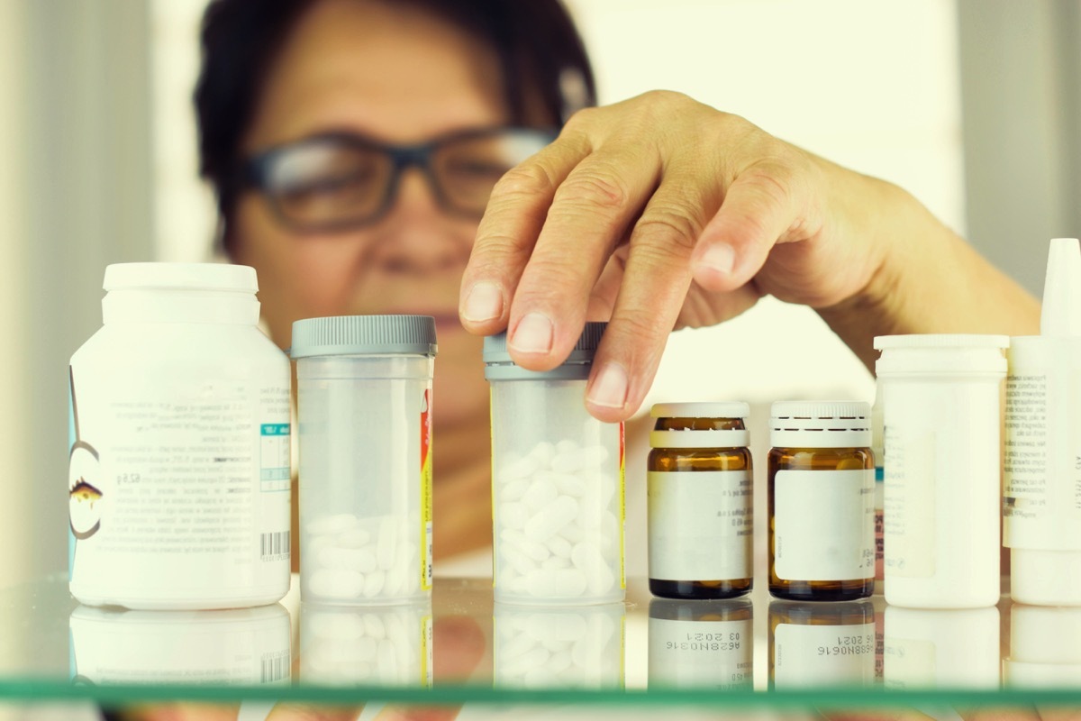 woman looking through her medications in her medicine cabinet, health questions after 50