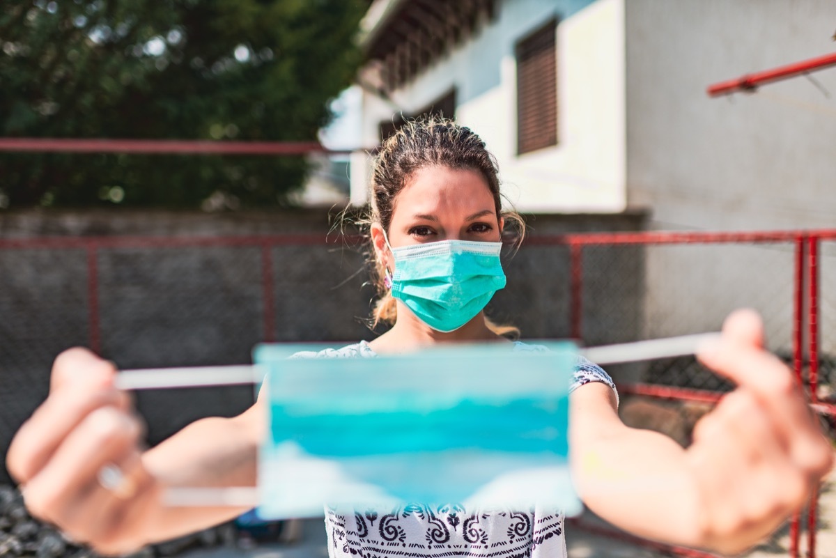 Woman wearing and applying pollution mask to someone else. They are outside.