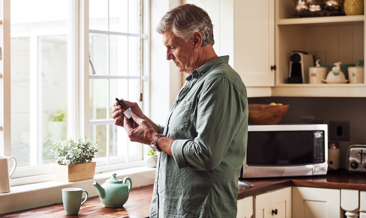 Cropped shot of a relaxed senior man preparing a cup of tea with CBD oil inside of it at home during the day