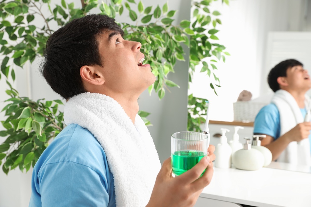 Man gargling mouthwash by his sink