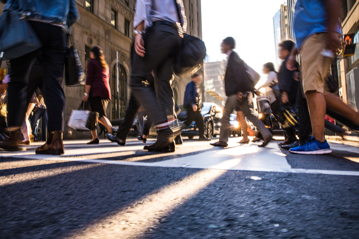 Pedestrians cross a busy crosswalk in the downtown area of a city.