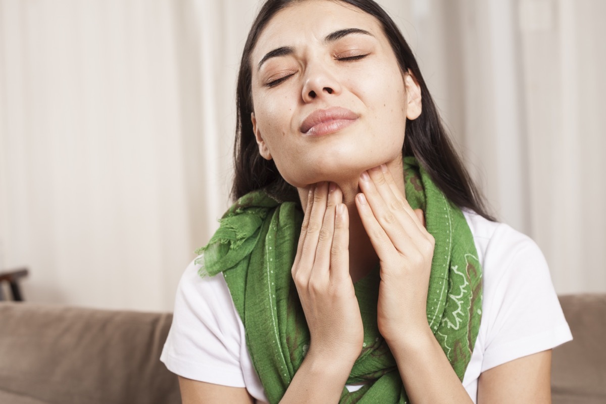 Woman touches her throat.