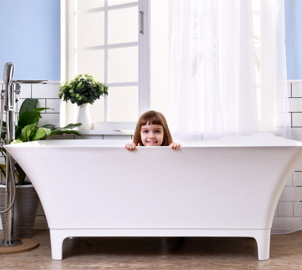 little girl peeking out of tub