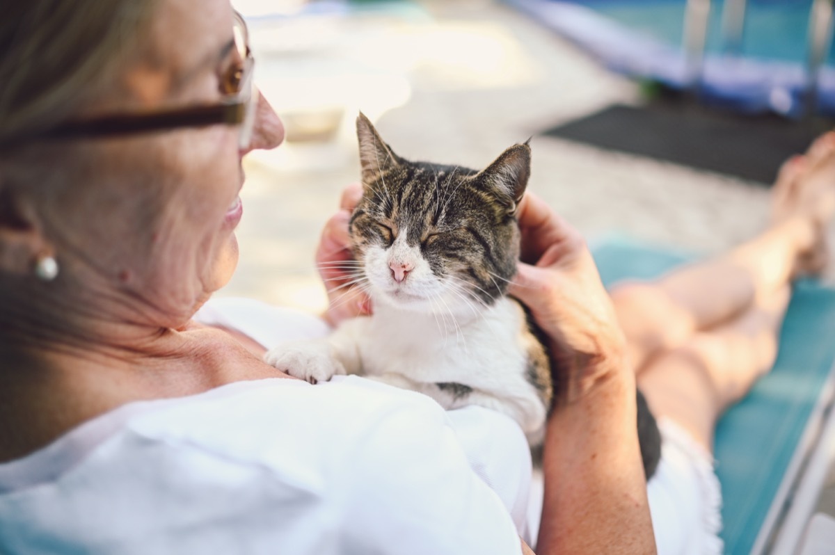 older woman sitting with cat on lounge chair