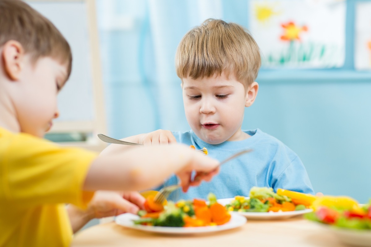 two white male toddlers eating vegetables