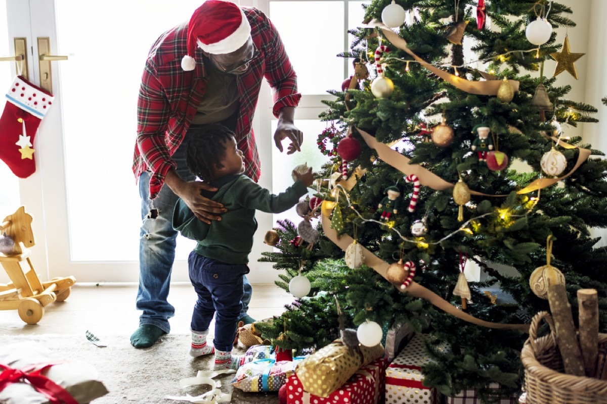 young black father and toddler son decorating christmas tree