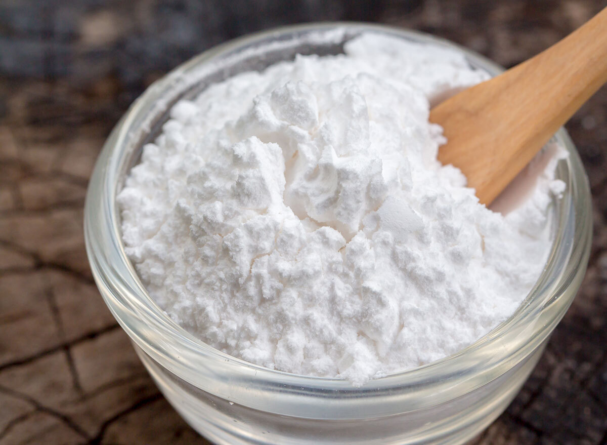 Baking powder in glass bowl with wooden spoon