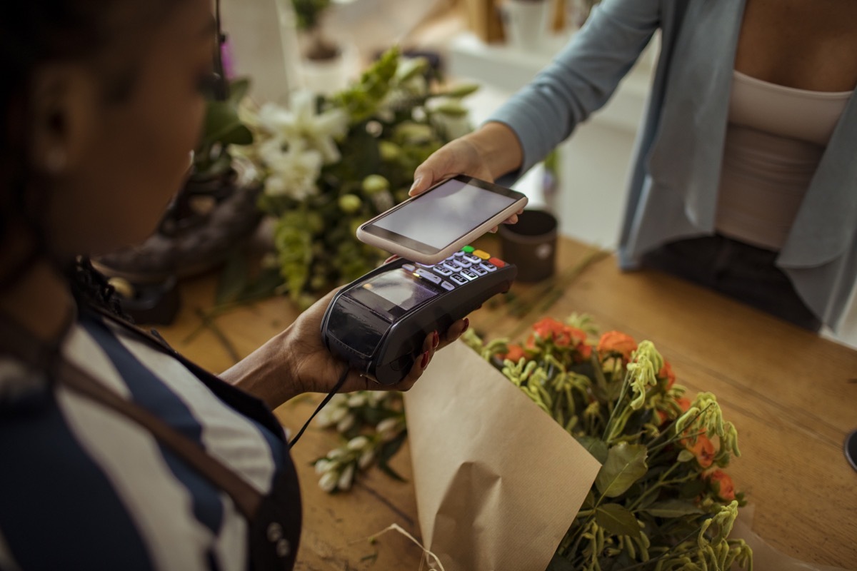 Close up of a young woman paying for a bouquet with her phone