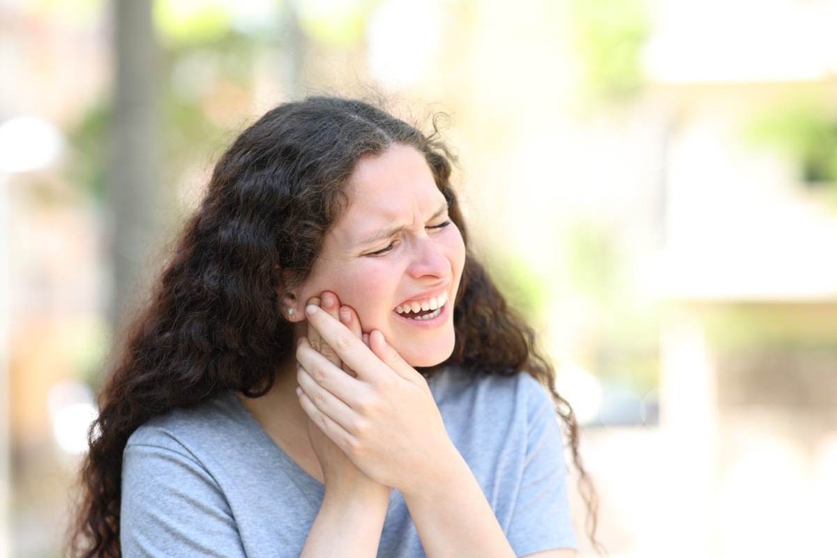 Woman suffering jaw ache in the street