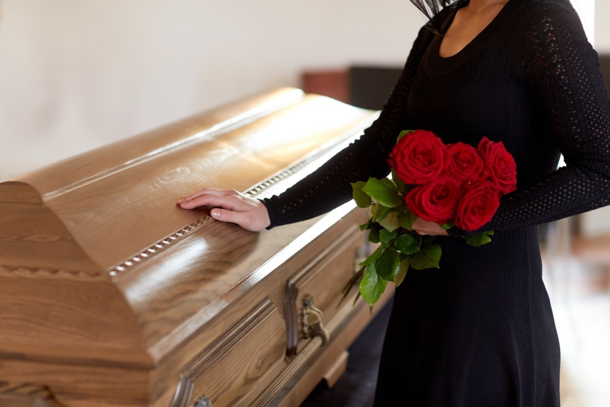 Woman at coffin with roses