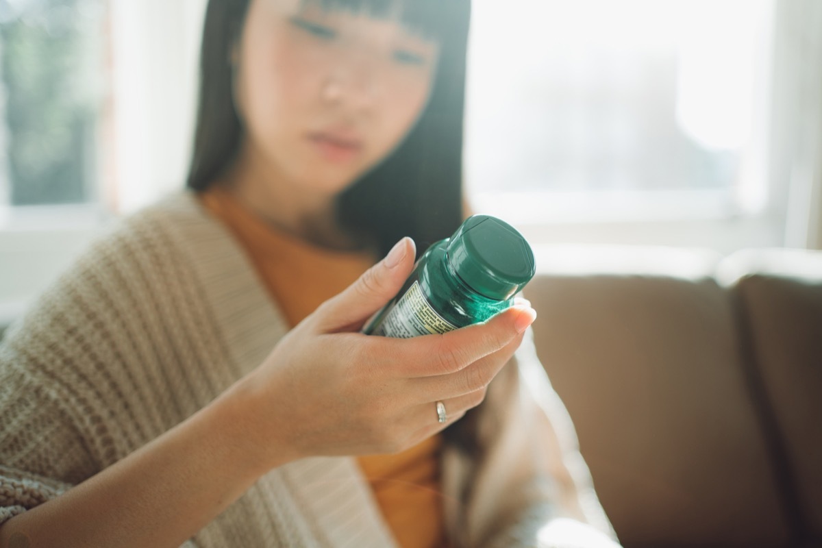 woman looking at supplement bottle