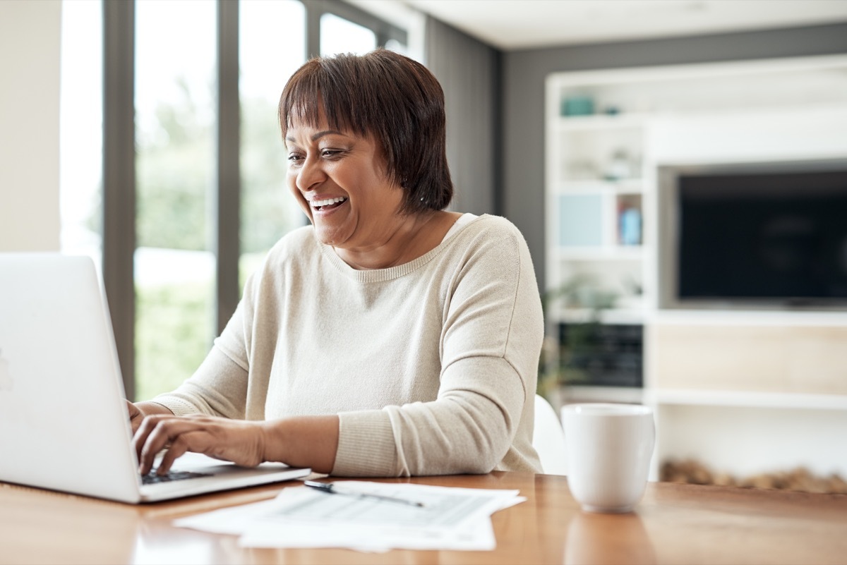 Cropped shot of a happy senior woman sitting alone and using a laptop in her living room at home