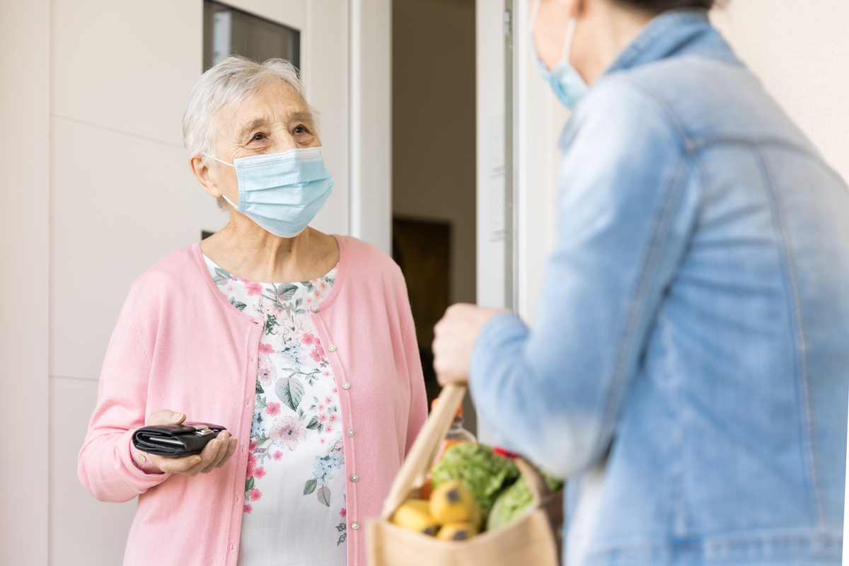 Woman delivering groceries to senior woman during quarantine