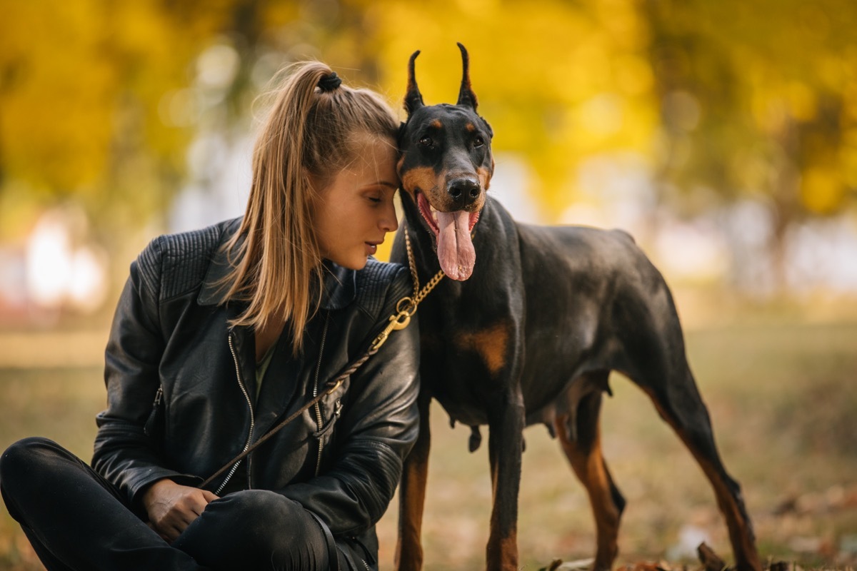 beautiful woman with her doberman pinscher in park outdoors.