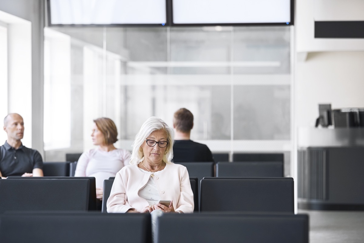 senior woman on her phone while she's in the waiting room