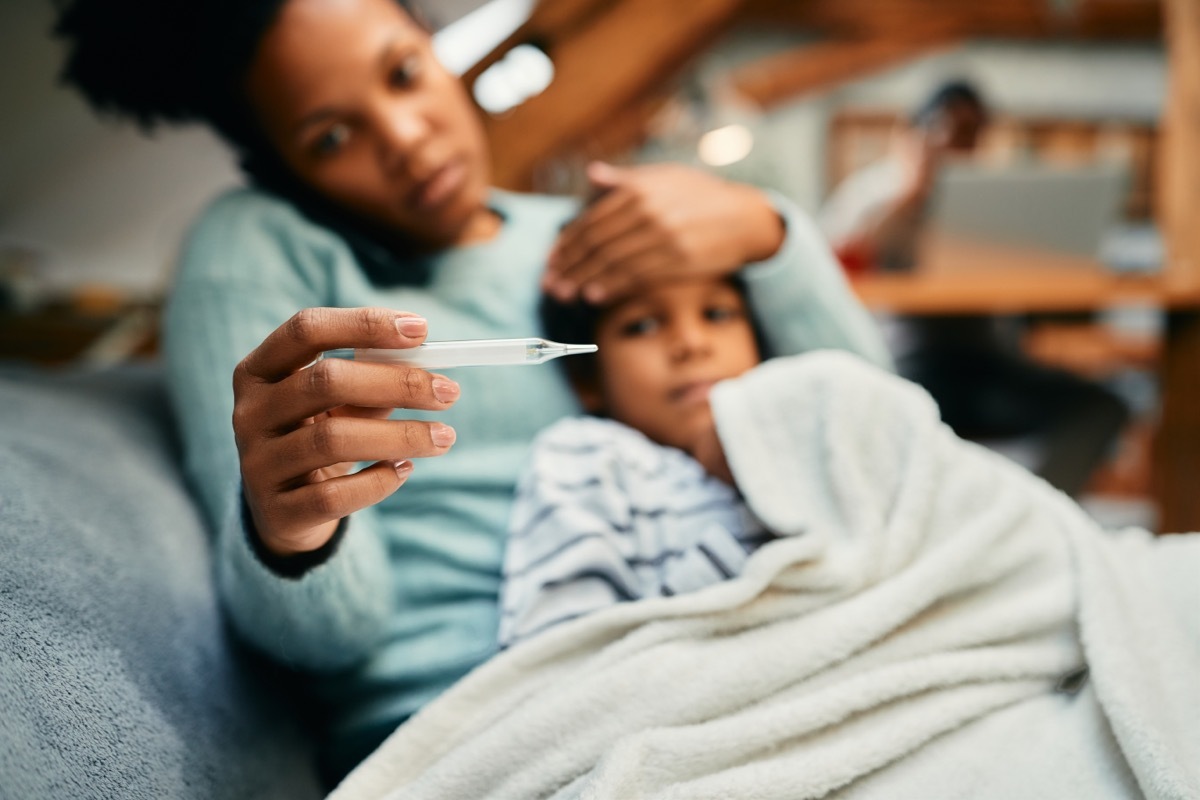 woman taking her sick child's temperature